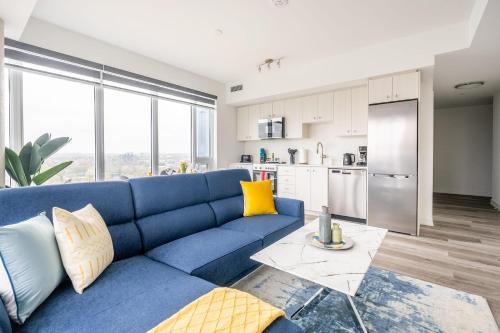 a living room with a blue couch and a kitchen at 1BR Modern Condo - King Bed and Stunning City View in Kitchener