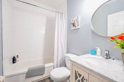 a white bathroom with a toilet and a sink at Corktown Apartment on James St South in Hamilton