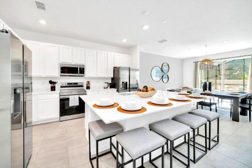 a kitchen with a large white table and chairs at 10BR Resort Home - Pool Hot tub Games - Near Disney in Kissimmee