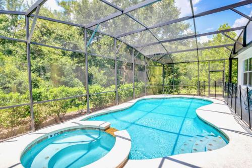 an indoor pool in a glass house with a swimming pool at Modern 6BR Home - Pool BBQ Hot Tub - Near Disney in Kissimmee