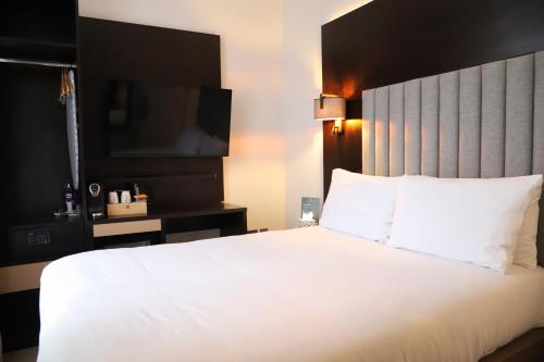 a bedroom with a large white bed and a television at Rove Hotel London Paddington in London