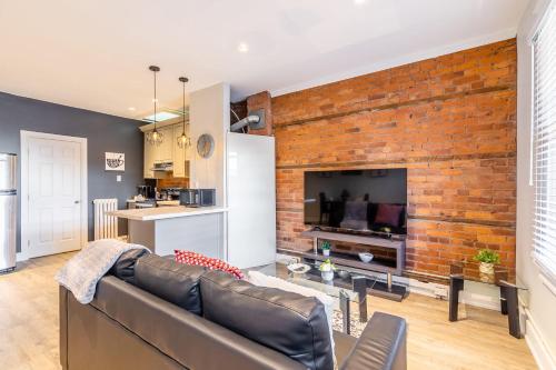 a living room with a brick wall and a couch at Hamilton's Best Neighbourhood 1BR Apartment in Hamilton