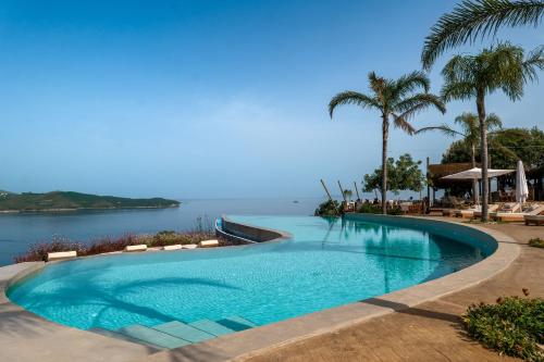 uma piscina ao lado de uma massa de água em Arameras Beach Resort em Ksamil