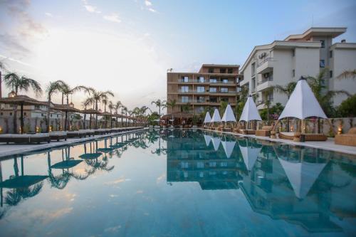 a pool of water with buildings and palm trees at Regina Palm Resort in Orikum