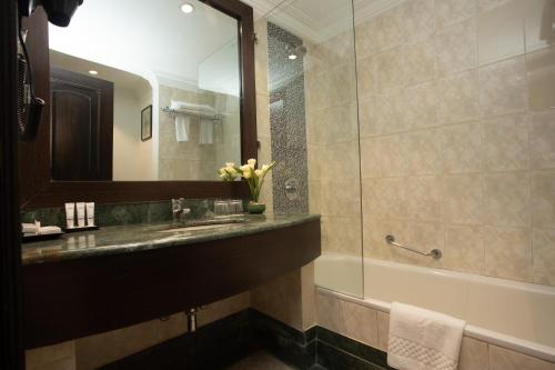 y baño con lavabo, espejo y bañera. en Grand Hotel Kathmandu, en Katmandú