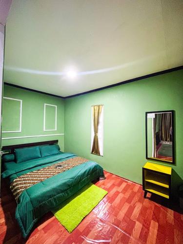 a green bedroom with a bed and a mirror at Green Savannah Homestay Syariah in Dieng
