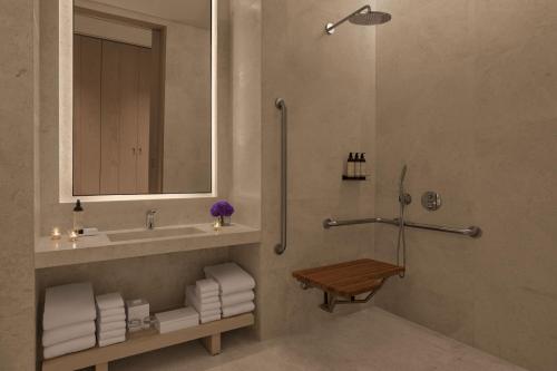 a bathroom with a sink and a shower with a mirror at The Jeddah EDITION in Jeddah