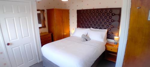 a bedroom with a white bed with a wooden headboard at Home and Away near the Spa in Bridlington