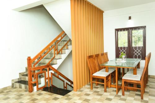 a dining room with a table and chairs and a staircase at The Cascade Munnar in Anachal