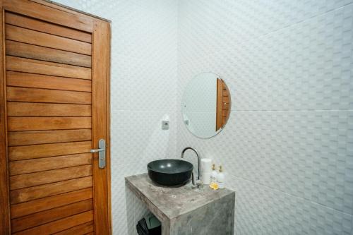 a bathroom with a sink and a mirror at Kubu Gena Guesthouse Canggu in Canggu