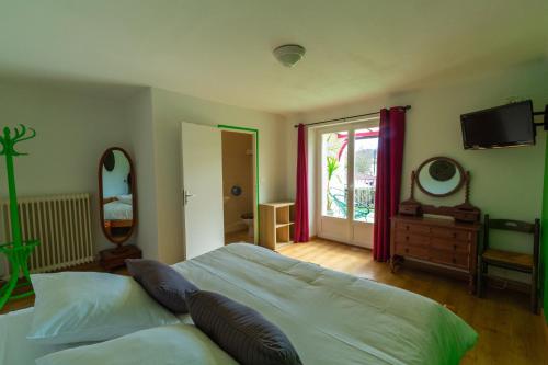 1 dormitorio con 1 cama, TV y ventana en Hôtel La Barguelonne en Montcuq