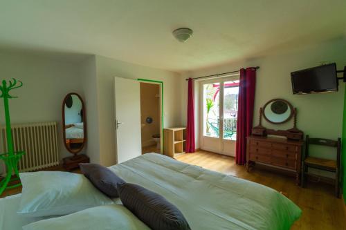a bedroom with a bed and a television and a window at Hôtel La Barguelonne in Montcuq