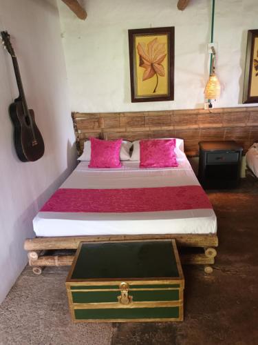 a bedroom with a bed with pink pillows and a guitar at Posadas rurales arabi in Pereira