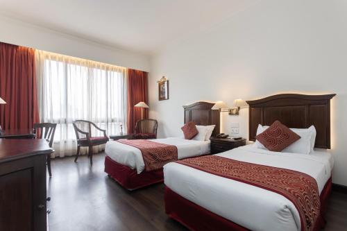 Habitación de hotel con 2 camas y escritorio en Grand Hotel Kathmandu, en Katmandú