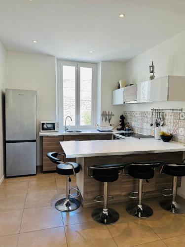 une cuisine avec un comptoir et des tabourets de bar dans l'établissement BEAU REZ DE JARDIN- Cannes Suquet - Clim- Calme - Lumineux- 15 minutes Palais des Festival, à Cannes