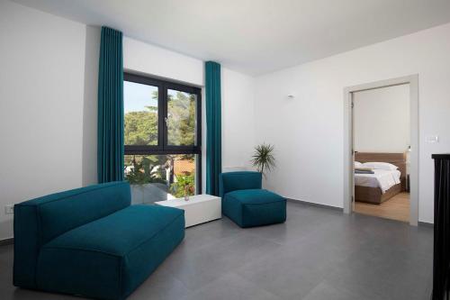 a living room with two blue chairs and a bed at Villa Rudina in Pomer
