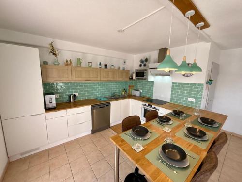 une cuisine avec une table en bois avec des chaises et du carrelage vert dans l'établissement L'Escapade Cathare - Résidence Terrasse & parking, à Carcassonne