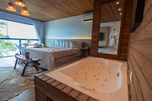 a bathroom with a tub and a bed with a mirror at Vila de Taipa Exclusive Hotel in Japaratinga