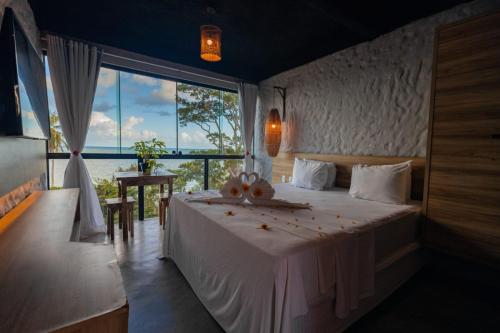 a bedroom with a large bed with a large window at Vila de Taipa Exclusive Hotel in Japaratinga