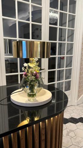 une table en verre avec un vase de fleurs dessus dans l'établissement Logis Hôtel Restaurant Grand Hôtel de Lyon, à Vals-les-Bains