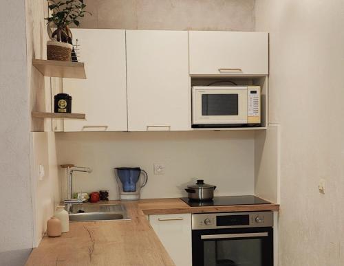 une cuisine avec des armoires blanches et un micro-ondes dans l'établissement Your lovely parisian 2 rooms apartment with private terrace - Jourdain, à Paris