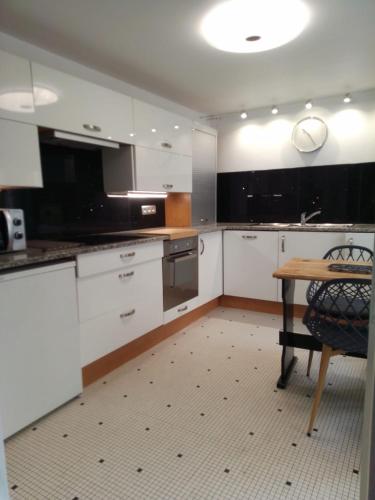 une cuisine avec des armoires blanches et une table en bois dans l'établissement T1bis, 100m de la belle plage de Morgat, à Crozon