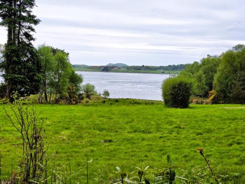 a field of green grass next to a body of water at Ard Veich Estate - Panoramic Highland Sea Views with private beach and woodland in Port Appin