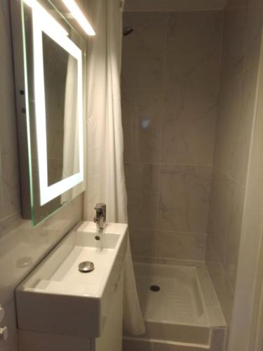 une salle de bain blanche avec un lavabo et une douche dans l'établissement T1bis, 100m de la belle plage de Morgat, à Crozon