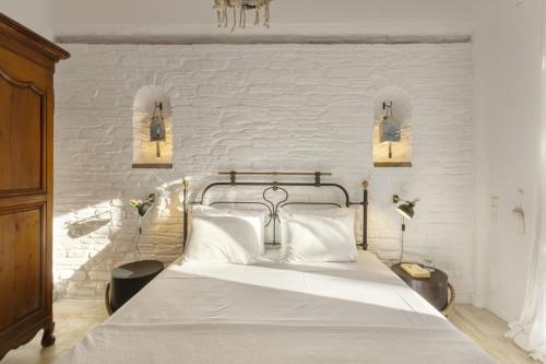 1 dormitorio blanco con 1 cama con paredes de ladrillo blanco en Seaside luxury villa, en Ándros