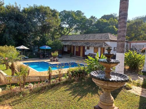 a fountain in the yard of a house with a pool at Pousada Santa Bárbara in Tiradentes