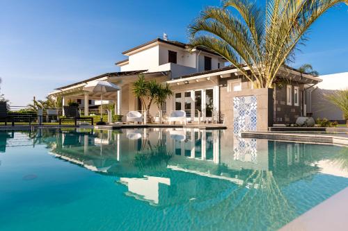 a house with a palm tree next to a swimming pool at Villa Solià - Villa indipendente con Piscina e Giardino in Campofelice di Roccella