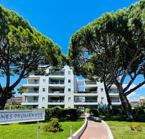 un edificio de apartamentos blanco con árboles delante de él en Cocon douillet face à la mer de Cagnes sur mer, en Cagnes-sur-Mer