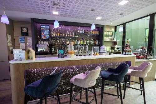 a bar with blue and white stools and a counter at Campanile Belfort Montbéliard - Gare La Jonxion. in Meroux