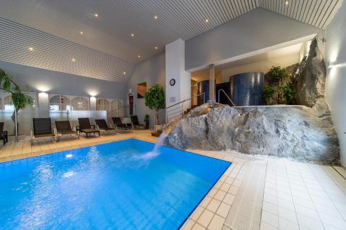 una gran piscina con cascada en una habitación de hotel en Koener Hotel & Spa en Clervaux
