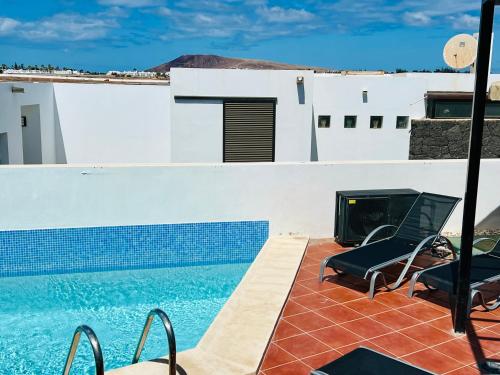a swimming pool with two chairs and a fireplace at Trendy Villa Isabella in Playa Blanca