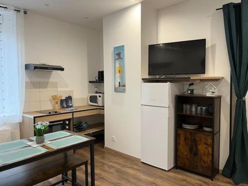 un salon avec une table et une télévision sur un mur dans l'établissement Le bleuet, à Montréjeau