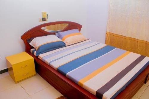 Bett mit einem Kopfteil aus Holz und Kissen darauf in der Unterkunft Appartement de Haut Standing à Abomey-Calavi in Abomey-Calavi