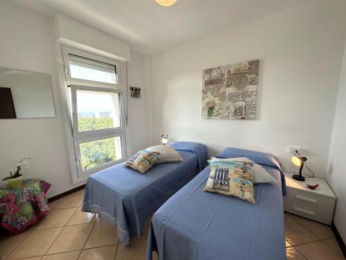 a bedroom with two blue beds and a window at Residence Torre Zanier in Lignano Sabbiadoro