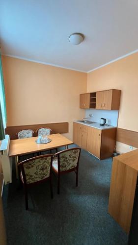 a room with a table and chairs and a kitchen at Grandhotel Nový Bor in Nový Bor