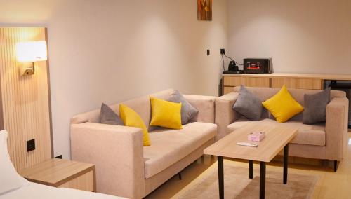 sala de estar con sofá y almohadas amarillas en بلند للشقق المخدومة, en Dammam