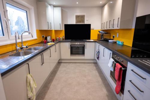 uma cozinha com armários brancos e bancadas pretas em Plas Gwyn Halls, Cardiff Met University em Cardiff