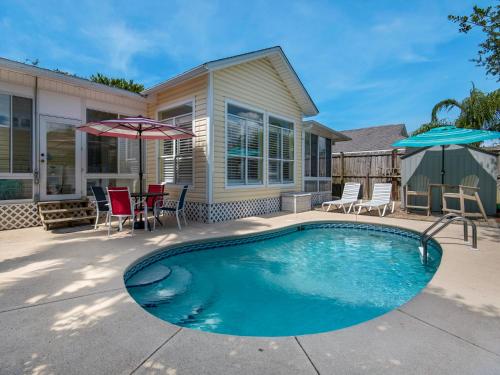 a swimming pool in front of a house with chairs and umbrellas at Caribbean Breeze by Newman-Dailey in Destin