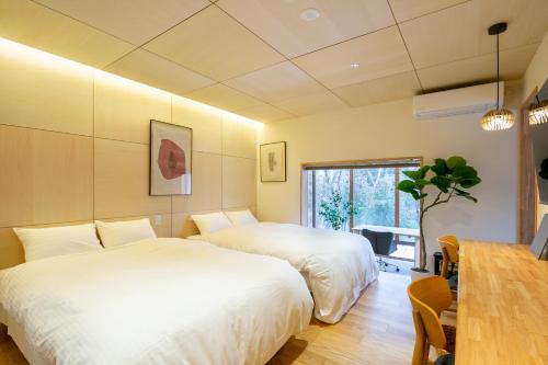 a bedroom with two beds and a table at Cooee Yamanakako in Yamanakako