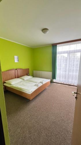 a bedroom with a bed with green walls and a window at Grandhotel Nový Bor in Nový Bor