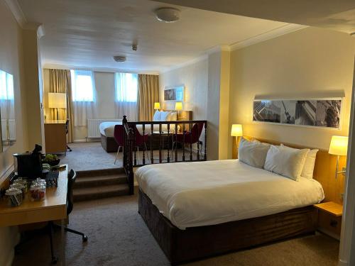 マンチェスターにあるブリタニア ホテル シティーセンター マンチェスターのベッドとデスクが備わるホテルルームです。