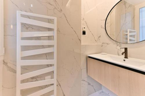 une salle de bain blanche avec un lavabo et un miroir dans l'établissement Charmant Appartement Paris Châtelet-Les Halles, à Paris