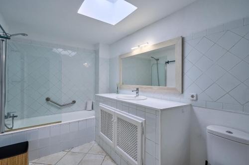 a white bathroom with a sink and a mirror at Villa Cala Dor in Santanyi