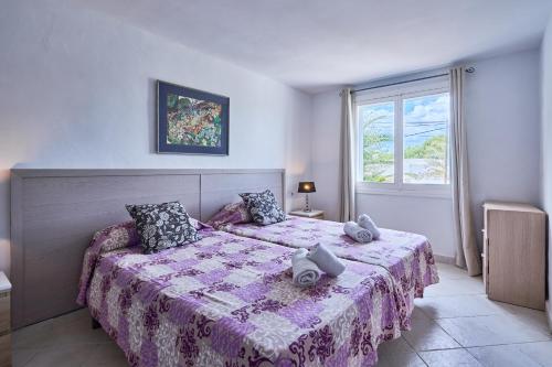 a bedroom with a bed with a purple blanket and a window at Villa Cala Dor in Santanyi