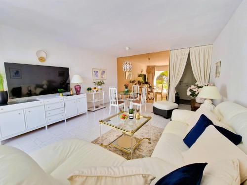 ein Wohnzimmer mit einem weißen Sofa und einem Fernseher in der Unterkunft Happy in Holiday Miraflores Apartments in Mijas