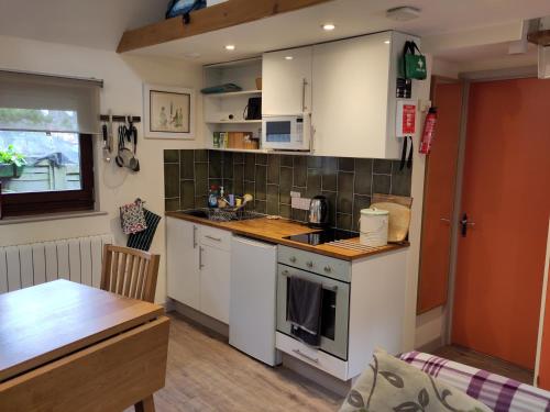 a kitchen with white cabinets and a wooden table at The Potting Shed Sopley in Christchurch